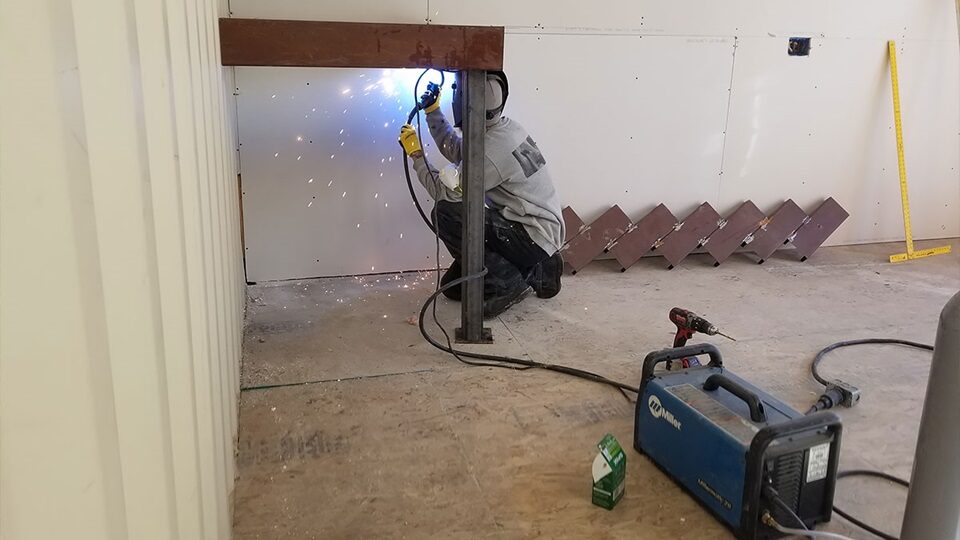 A welder working inside a steel container